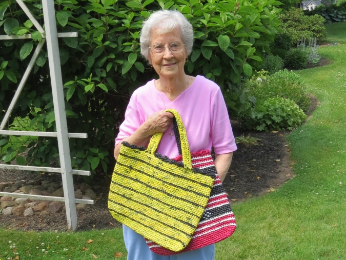 Arlette Sherwood displays two of the hundreds of carry bags she has crocheted using throw-away plastic retail bags.